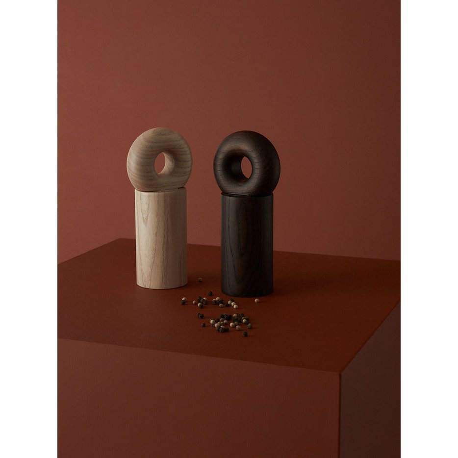 Two wooden salt and pepper grinders on a red surface with a plain background