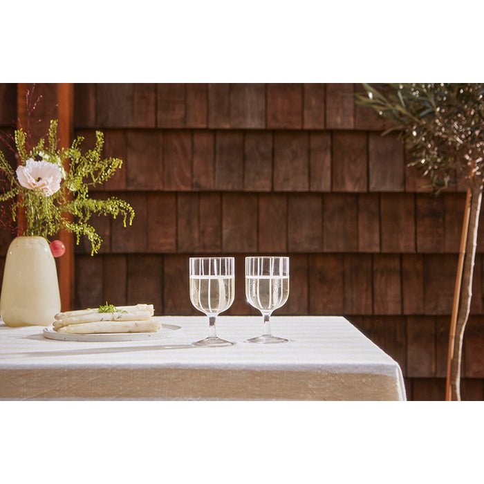 Two wine glasses on a table with a wooden fence background