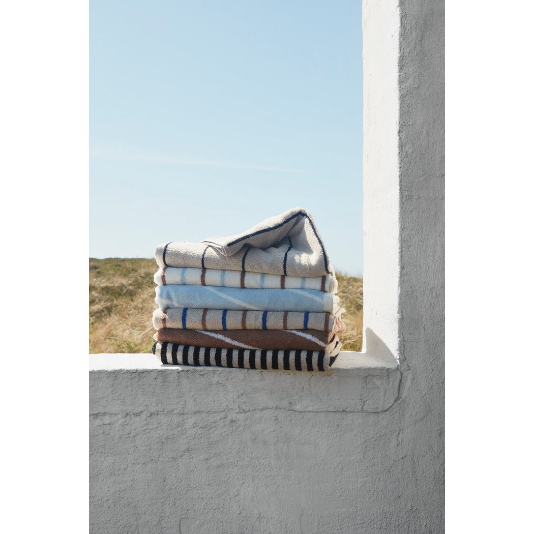 Stack of folded towels on a ledge with a clear blue sky in the background