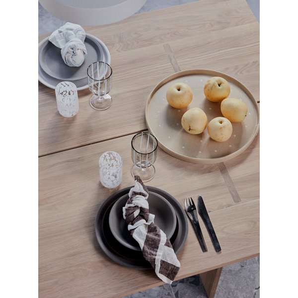 Dining table setting with plates, glasses, and apples on a wooden surface.