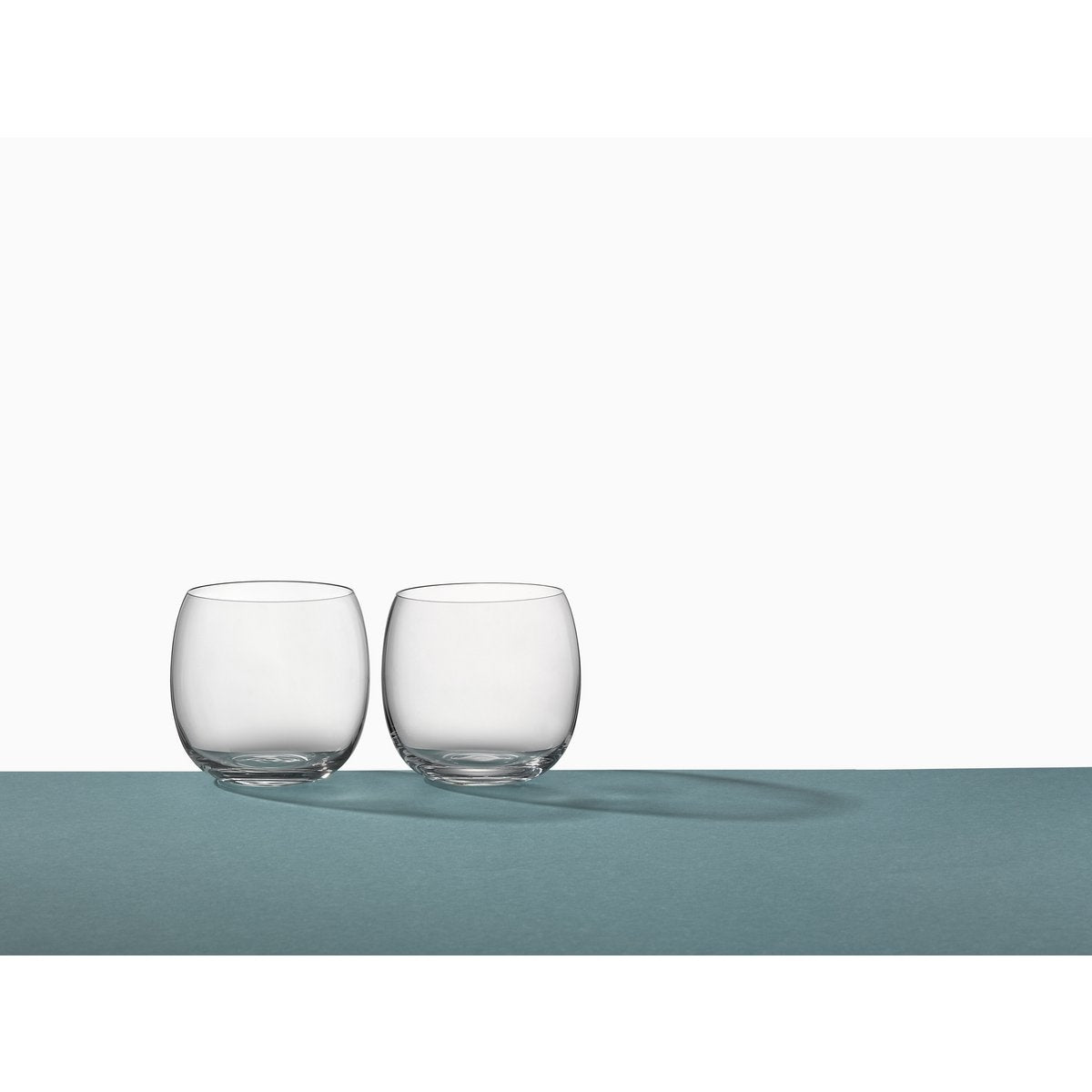 Two clear glass tumblers on a light gray surface with a white background