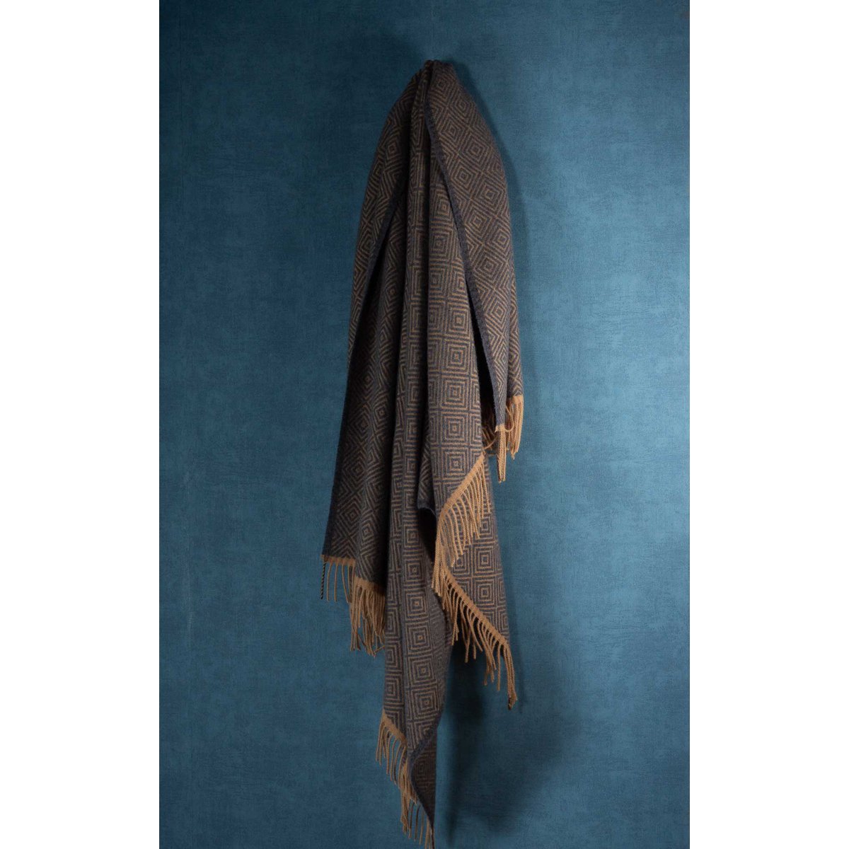 Brown woven blanket with fringes on a blue background