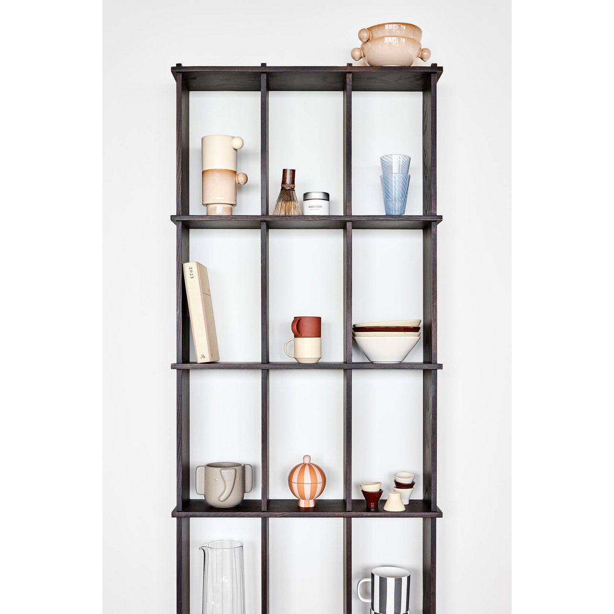 Tall dark wooden bookshelf with decorative items against a white wall