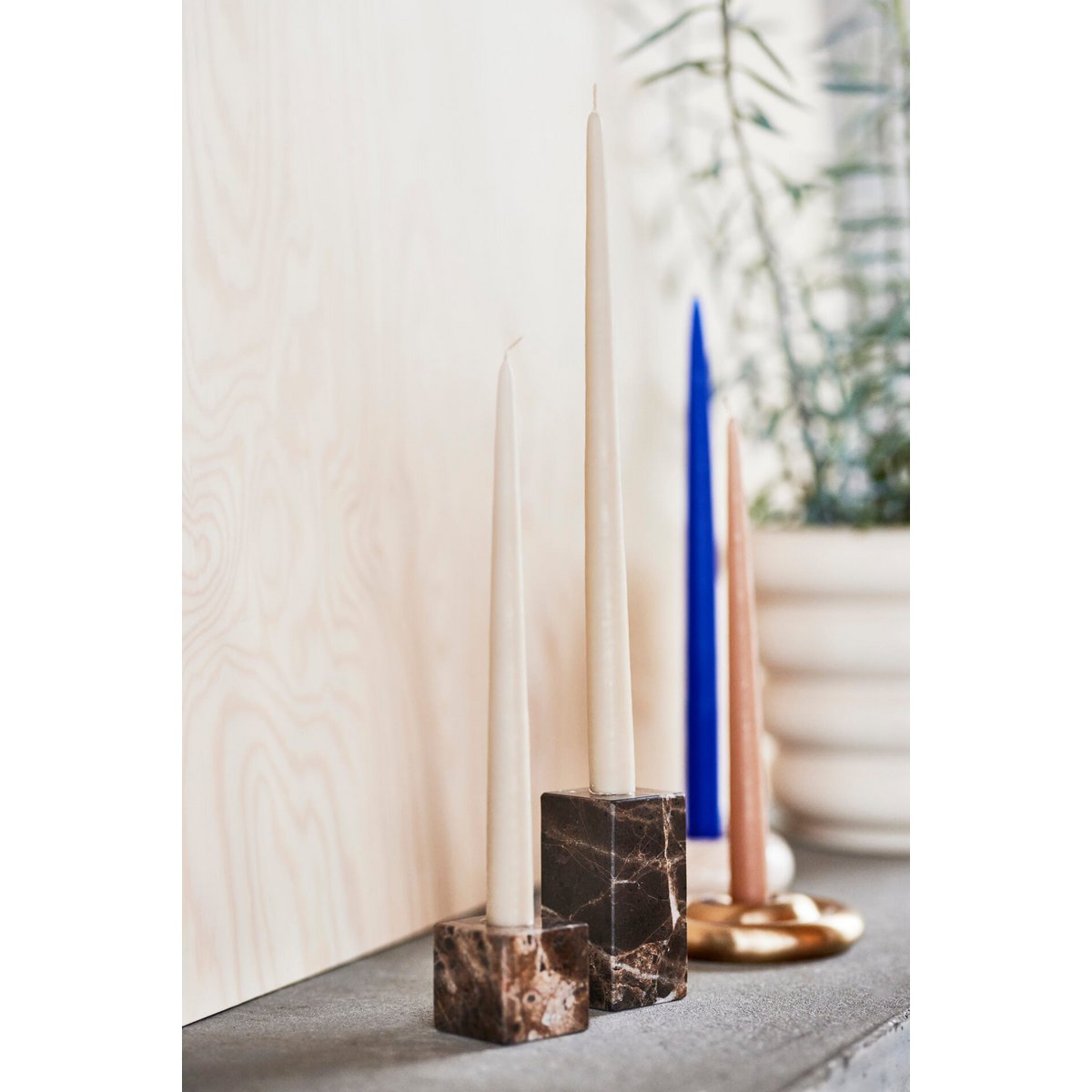 Decorative candles in marble and brass candle holders on a neutral background