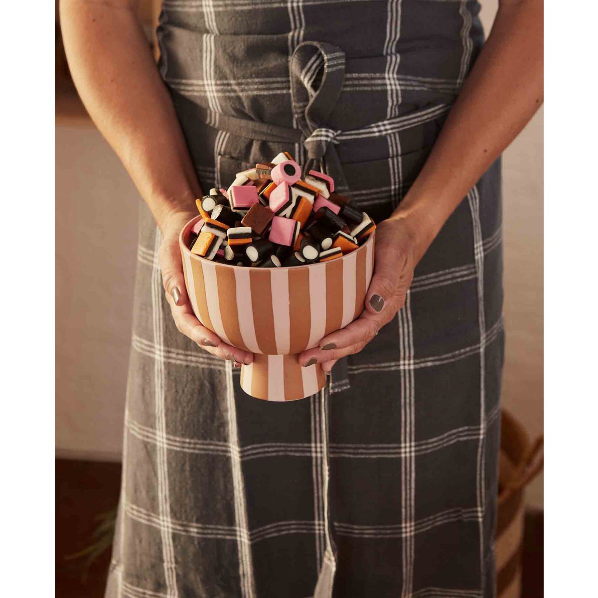Person holding a striped bowl filled with colorful dog toys.