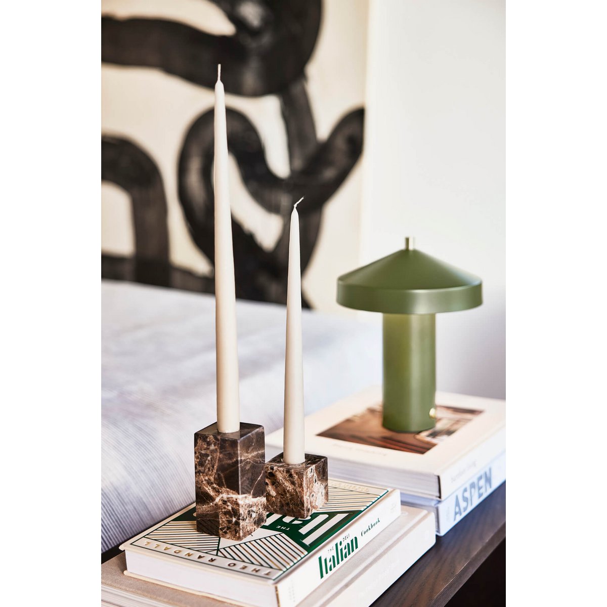 Decorative candle holder with candles on books against a patterned wall