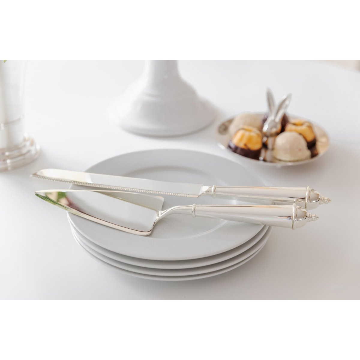 Silver cutlery set on a stack of white plates with a blurred background