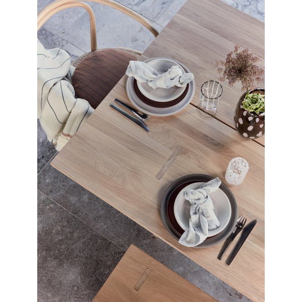 Dining table set with plates, cutlery, and glasses on a stone floor.