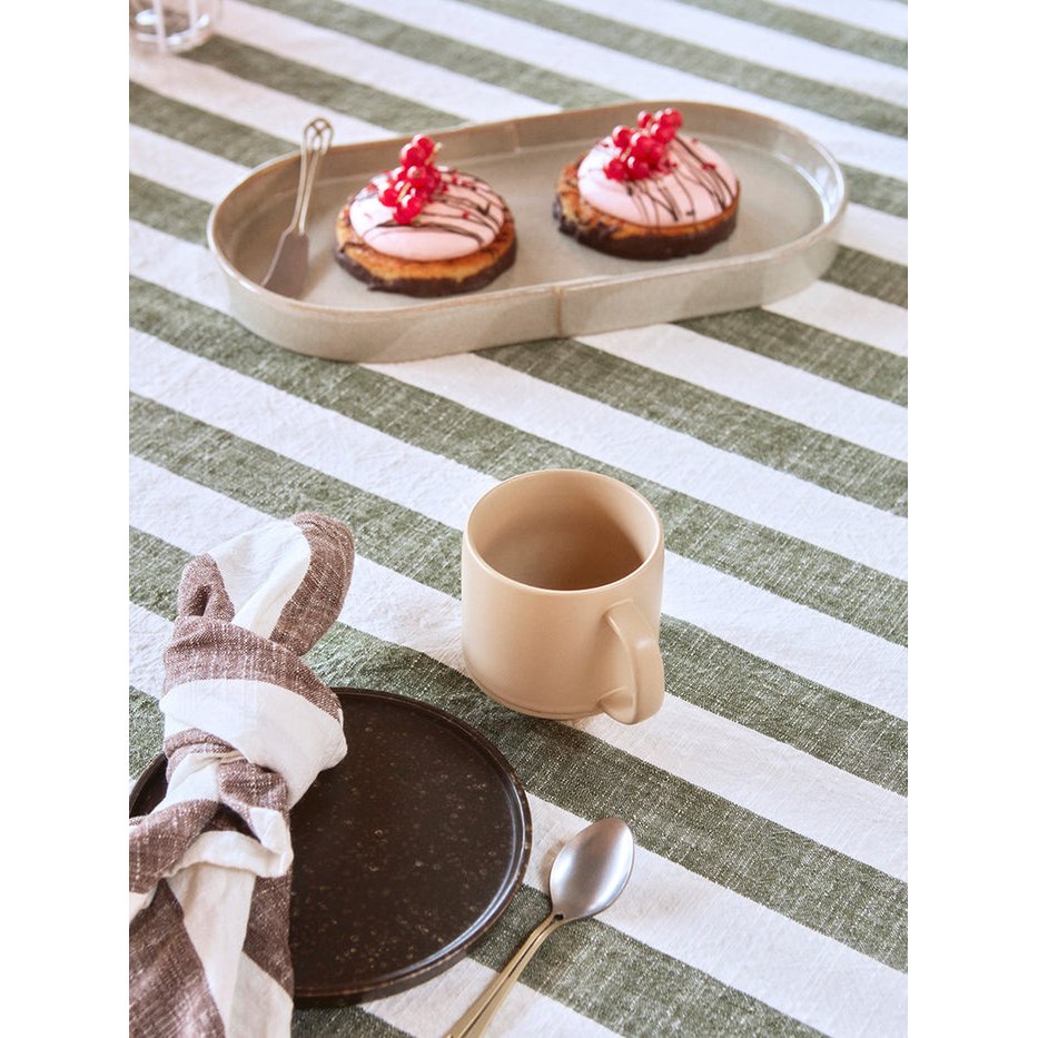 Ceramic mug, plate, and dessert on a striped tablecloth