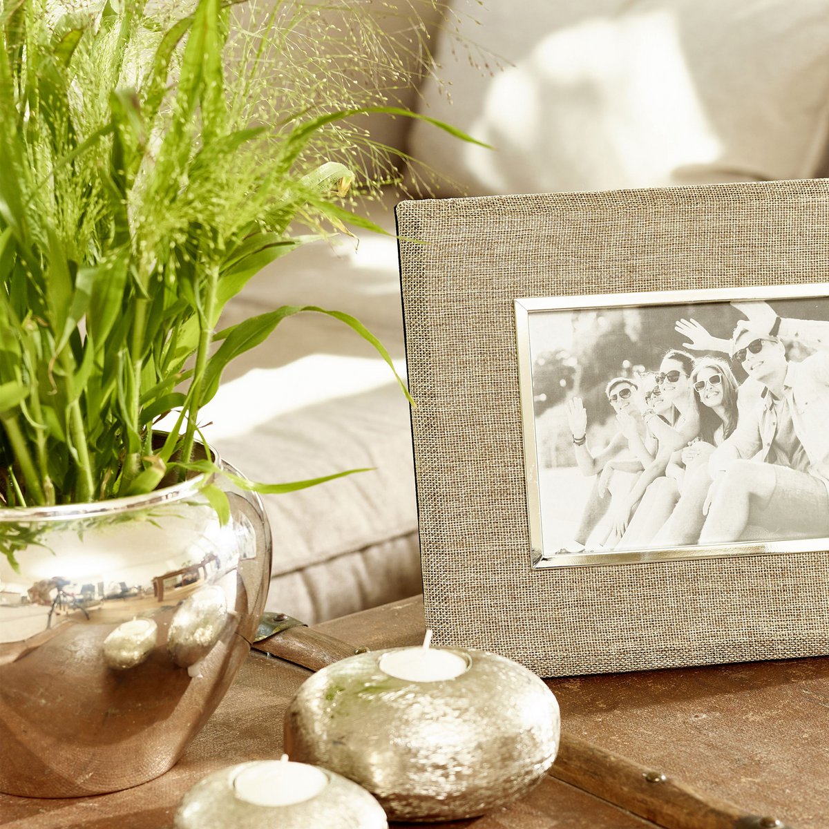 Decorative setting with a plant, candles, and a framed photo on a wooden surface.