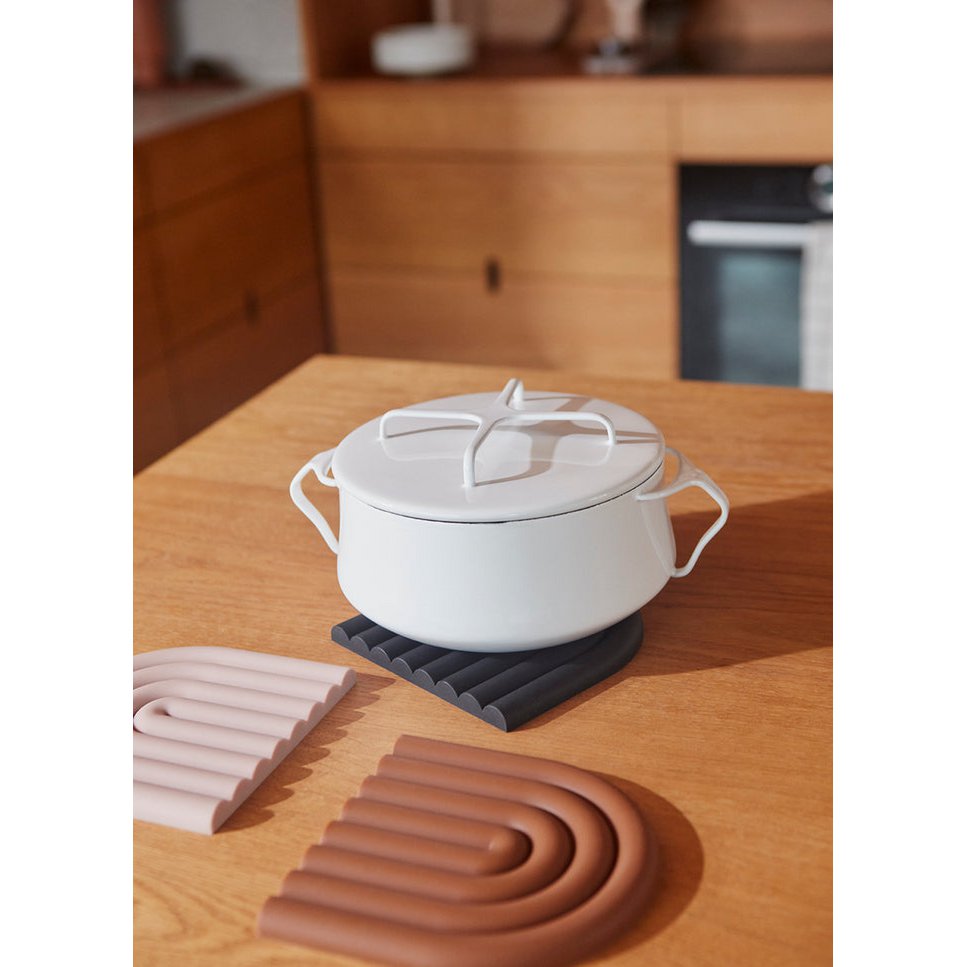 White pot with a lid on a wooden table with silicone bands in the foreground