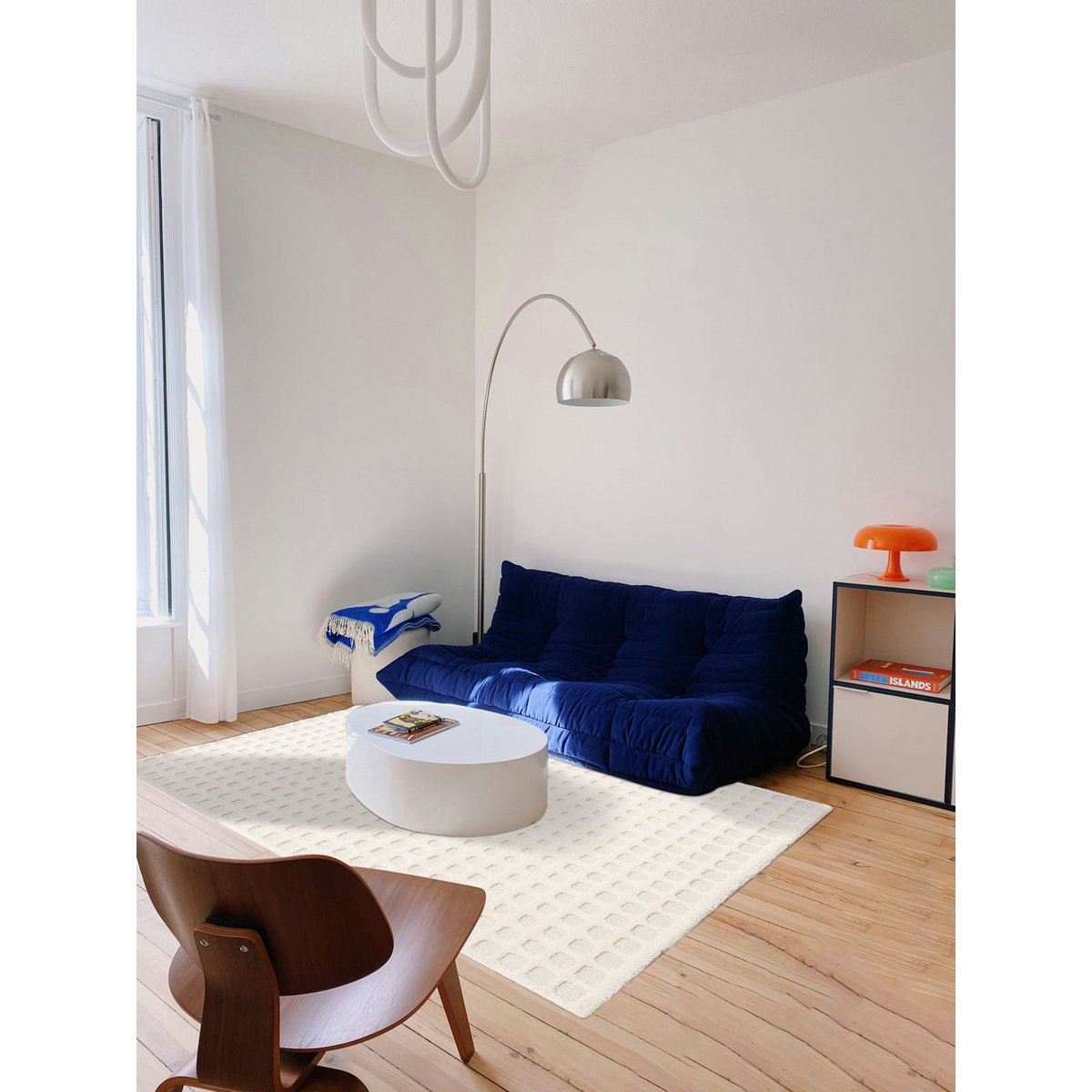 Modern living room with a blue sofa, white coffee table, and wooden floor.