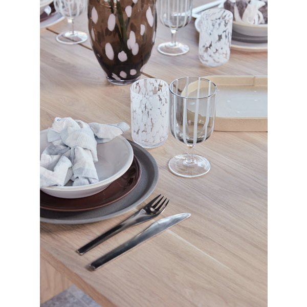 Dining table setting with plates, glasses, and cutlery on a wooden surface.