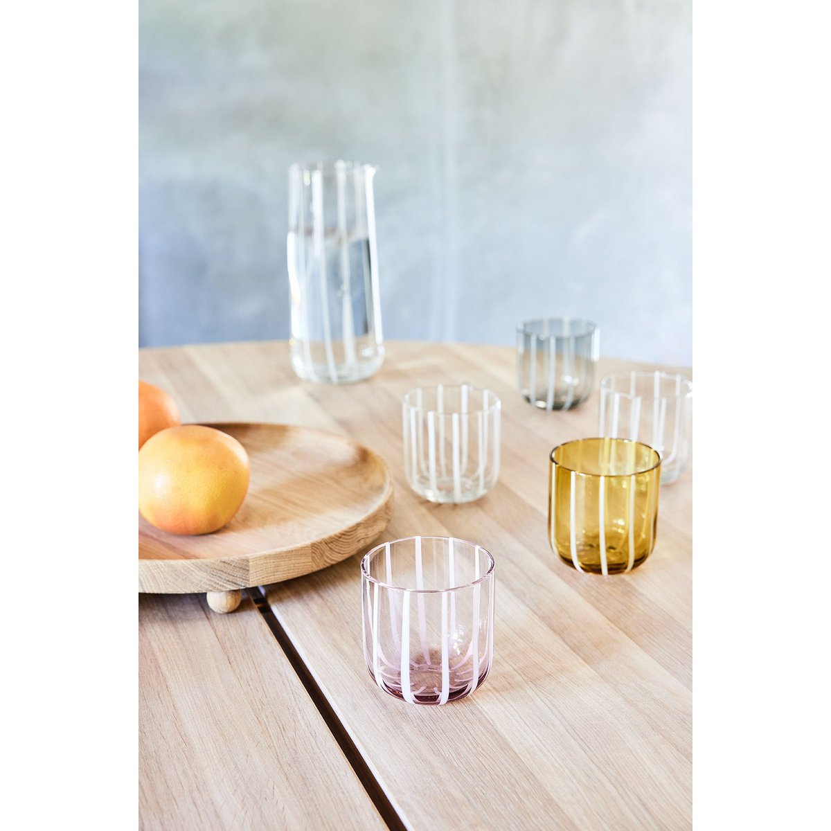 Set of colorful glass tumblers on a wooden table with a light background