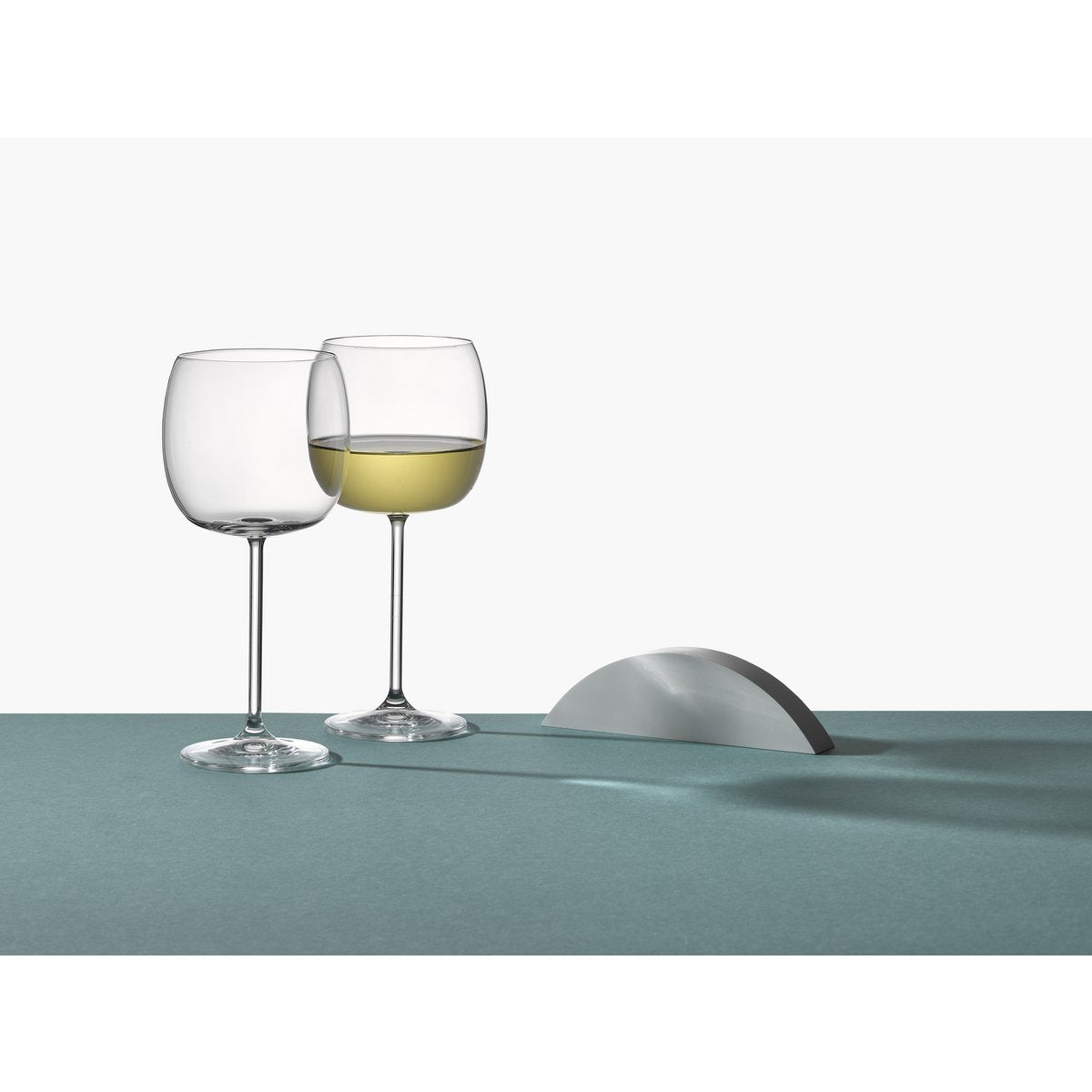 Two wine glasses with white wine on a light blue surface