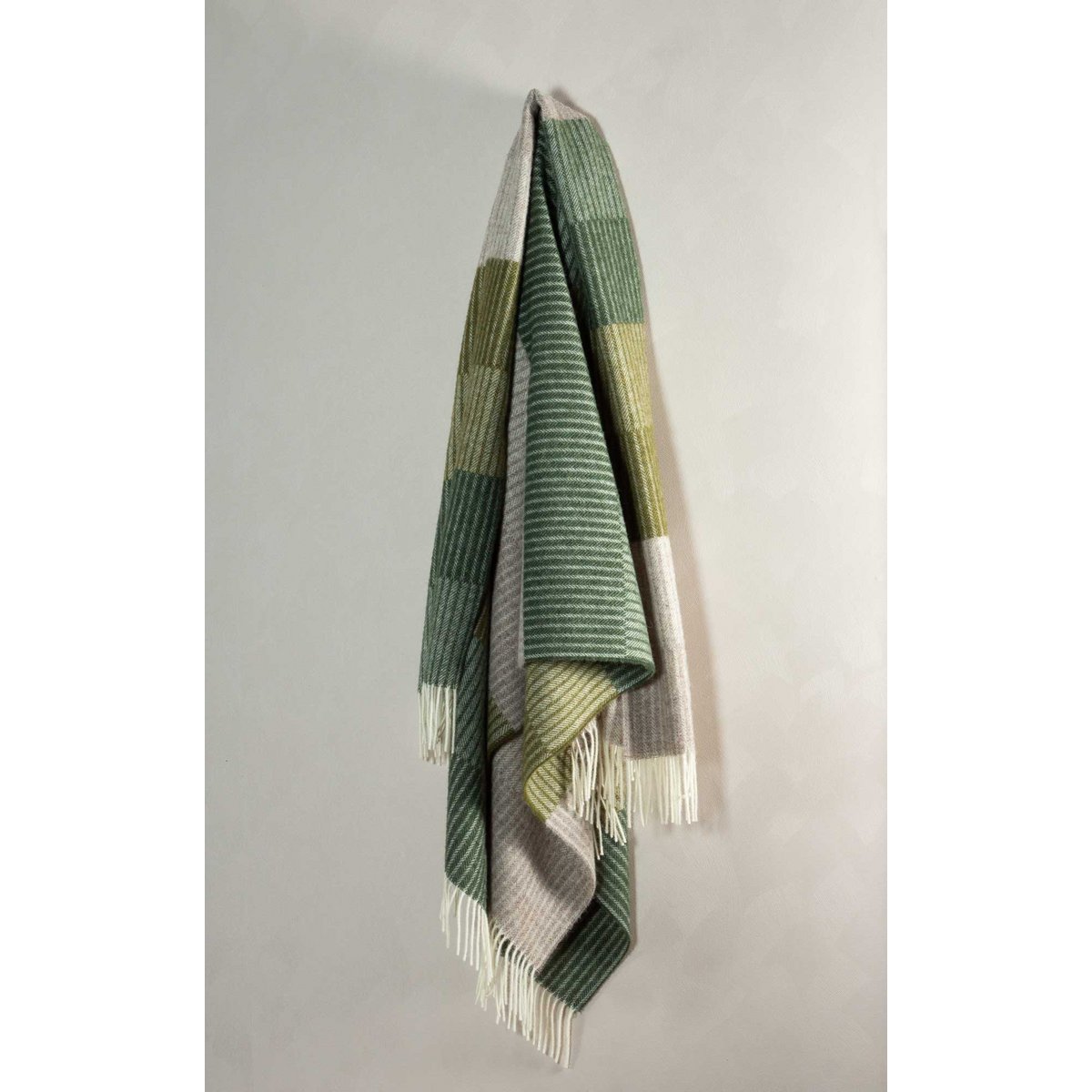Green and white striped blanket draped over a gray wall