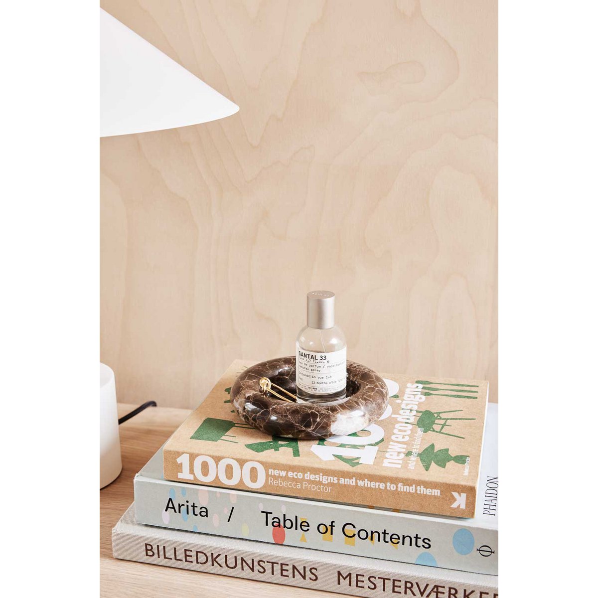 Bottle on a marble candleholder on top of books with a wooden surface