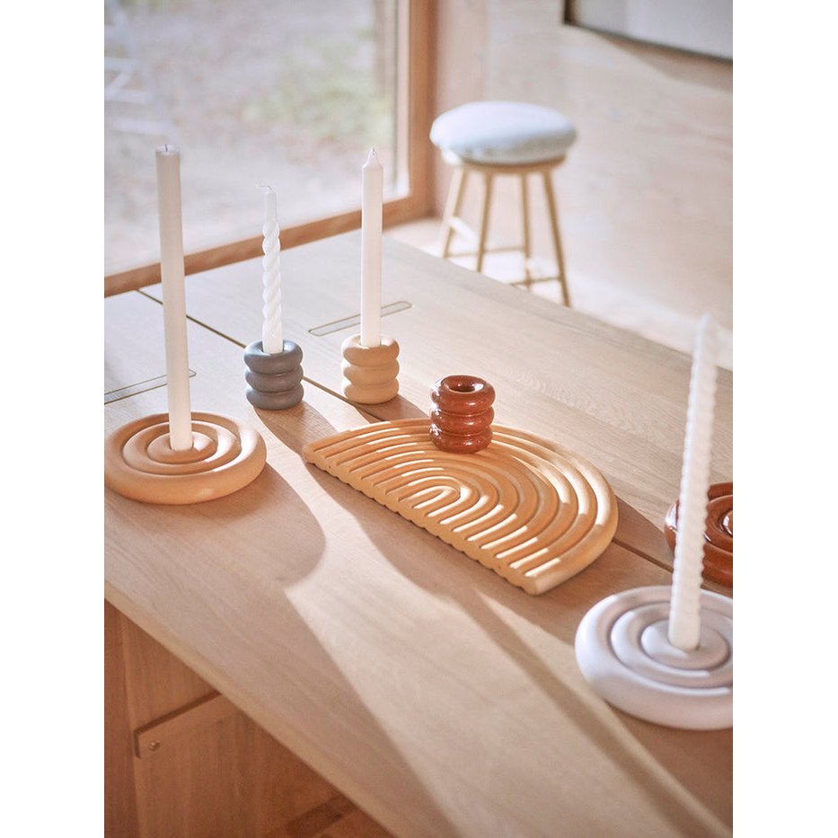 Candle holders on a wooden surface with a stool in the background