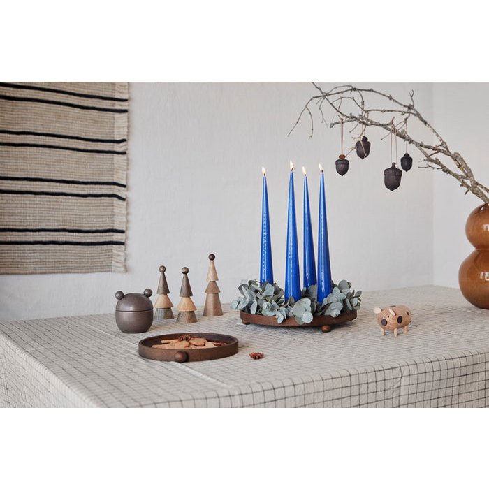 Decorative setup with blue candles, small sculptures, and a branch on a checkered tablecloth.