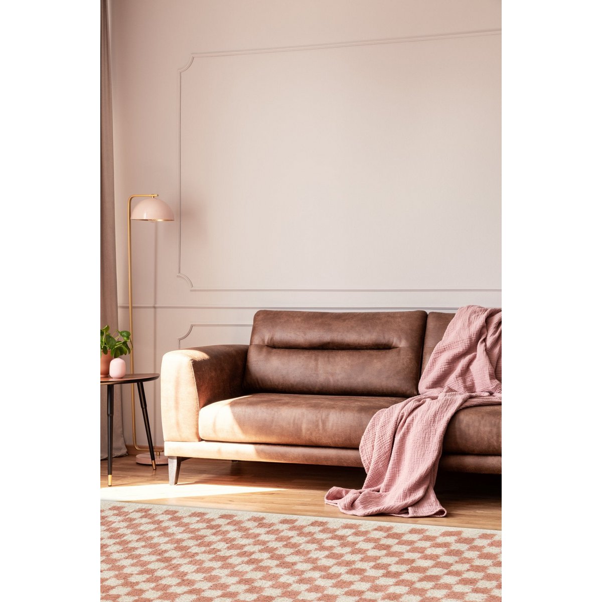 Brown sofa with a pink blanket in a living room setting