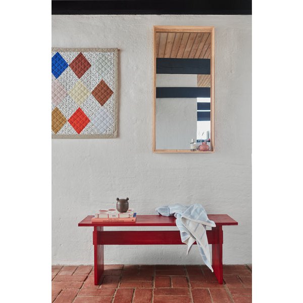 Red table with a white cloth draped over it, against a wall with a mirror and abstract art.