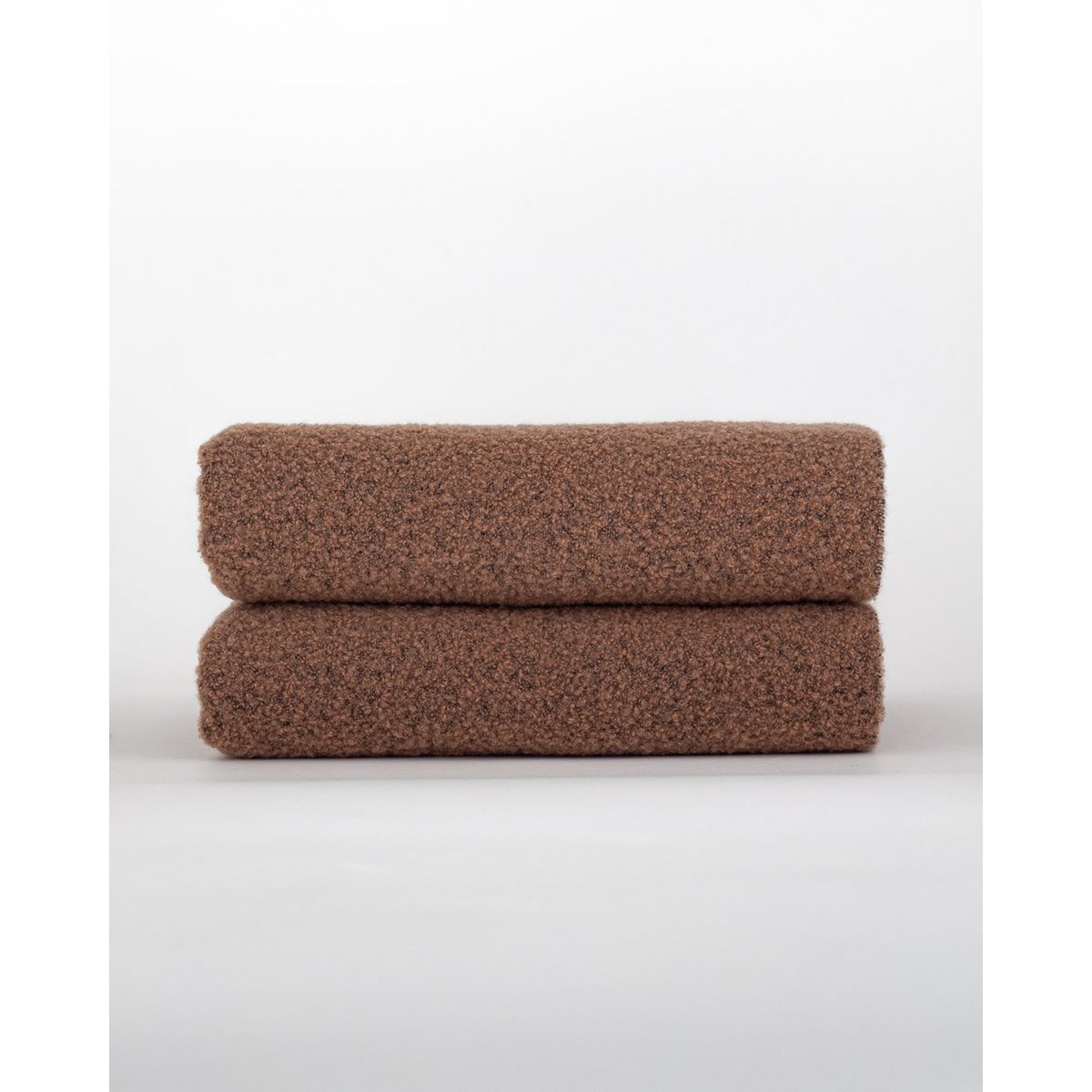 Two brown towels stacked on a white background