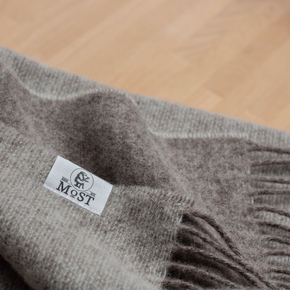 Gray blanket with a brand label on a wooden surface