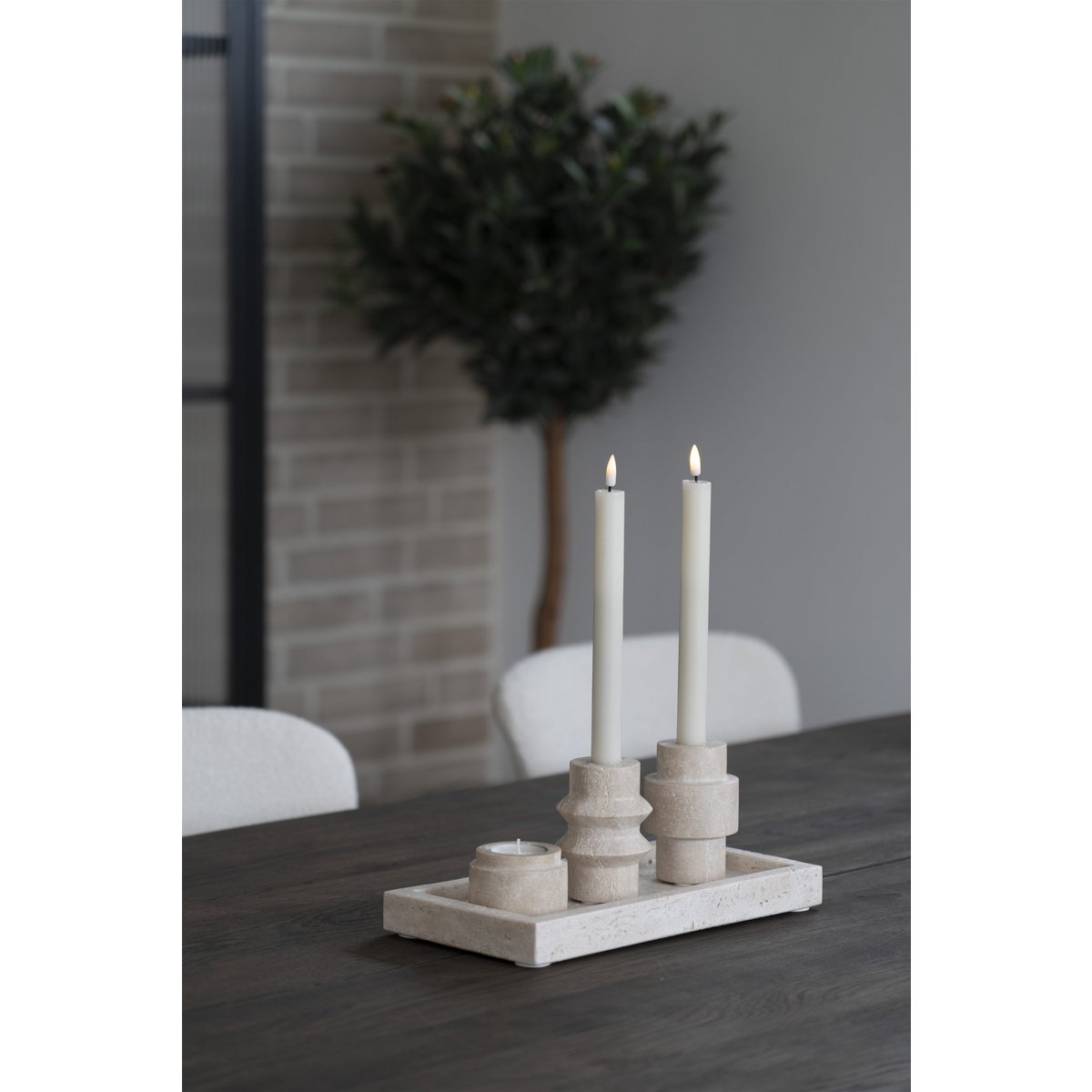 Candle holder with candles on a table in a room with a plant in the background