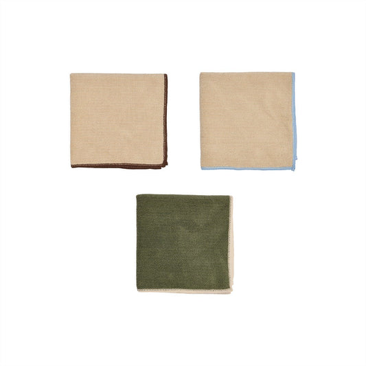 Three folded fabric napkins in beige, green, and another shade of beige on a white background.