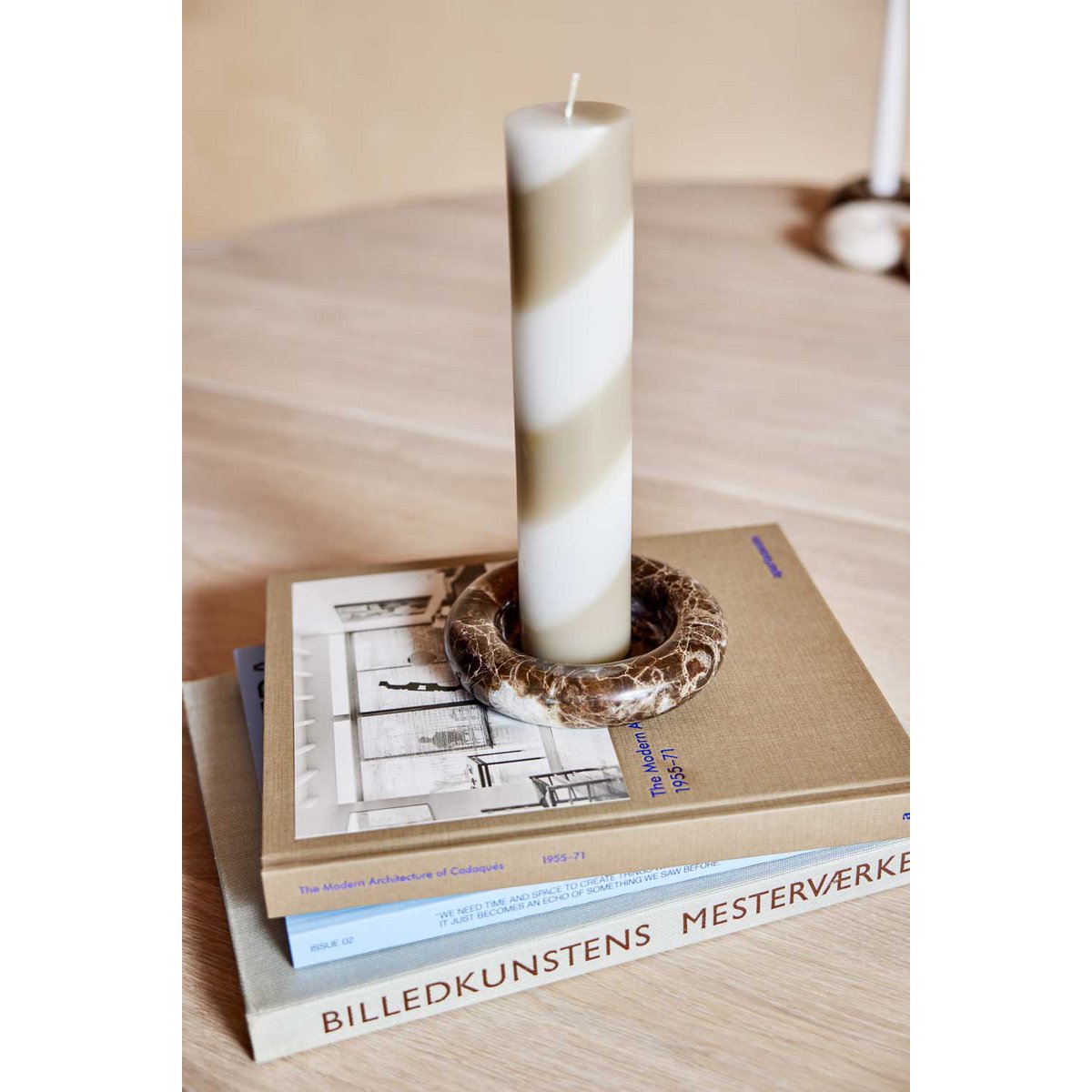 Candle in a decorative holder on top of books with a blurred background