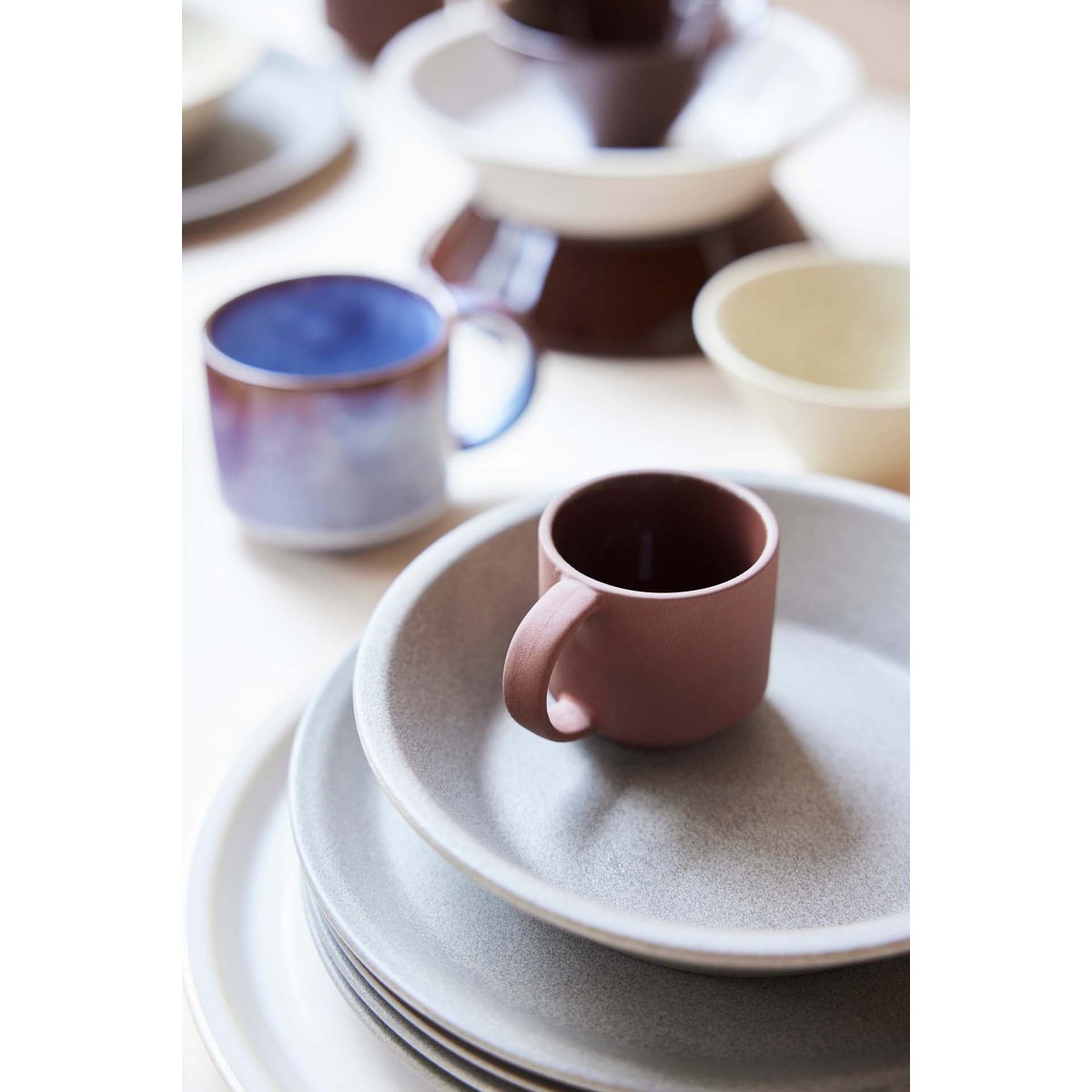 Ceramic mugs and plates with gradient colors on a white surface