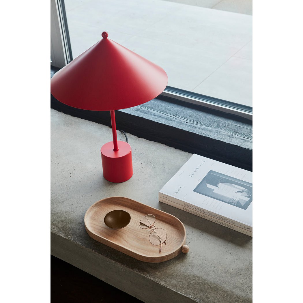 Red table lamp on a windowsill with a wooden tray and glasses nearby