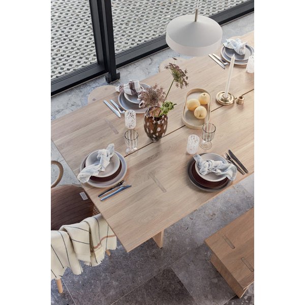 Dining table set with plates, glasses, and cutlery in a modern indoor setting.