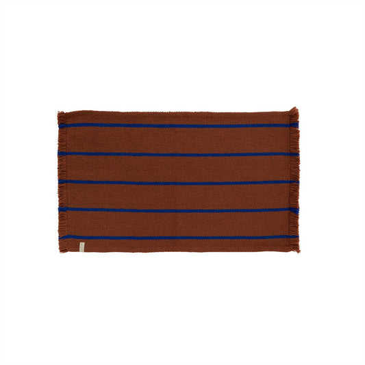 Caramel woven mat with blue stripes on a white background