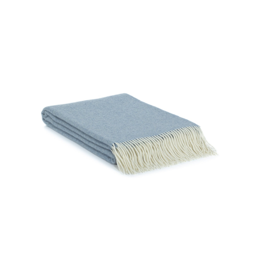 Folded blue throw blanket with white fringe on a white background