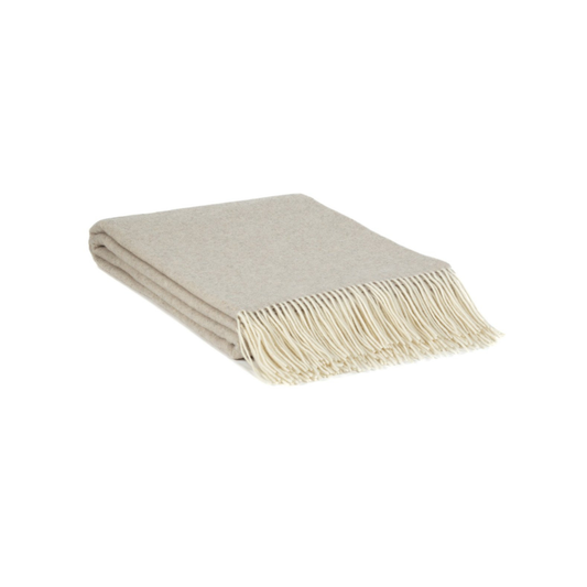 Folded beige blanket with white fringe on a white background