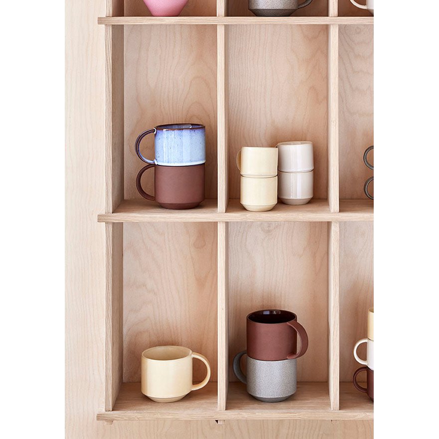 Wooden shelf with ceramic mugs of various colors