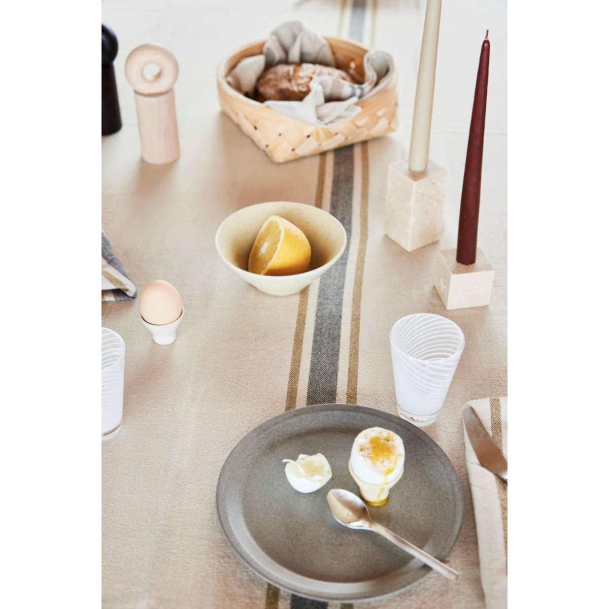 Table setting with a cracked egg on a plate, surrounded by minimal decor.