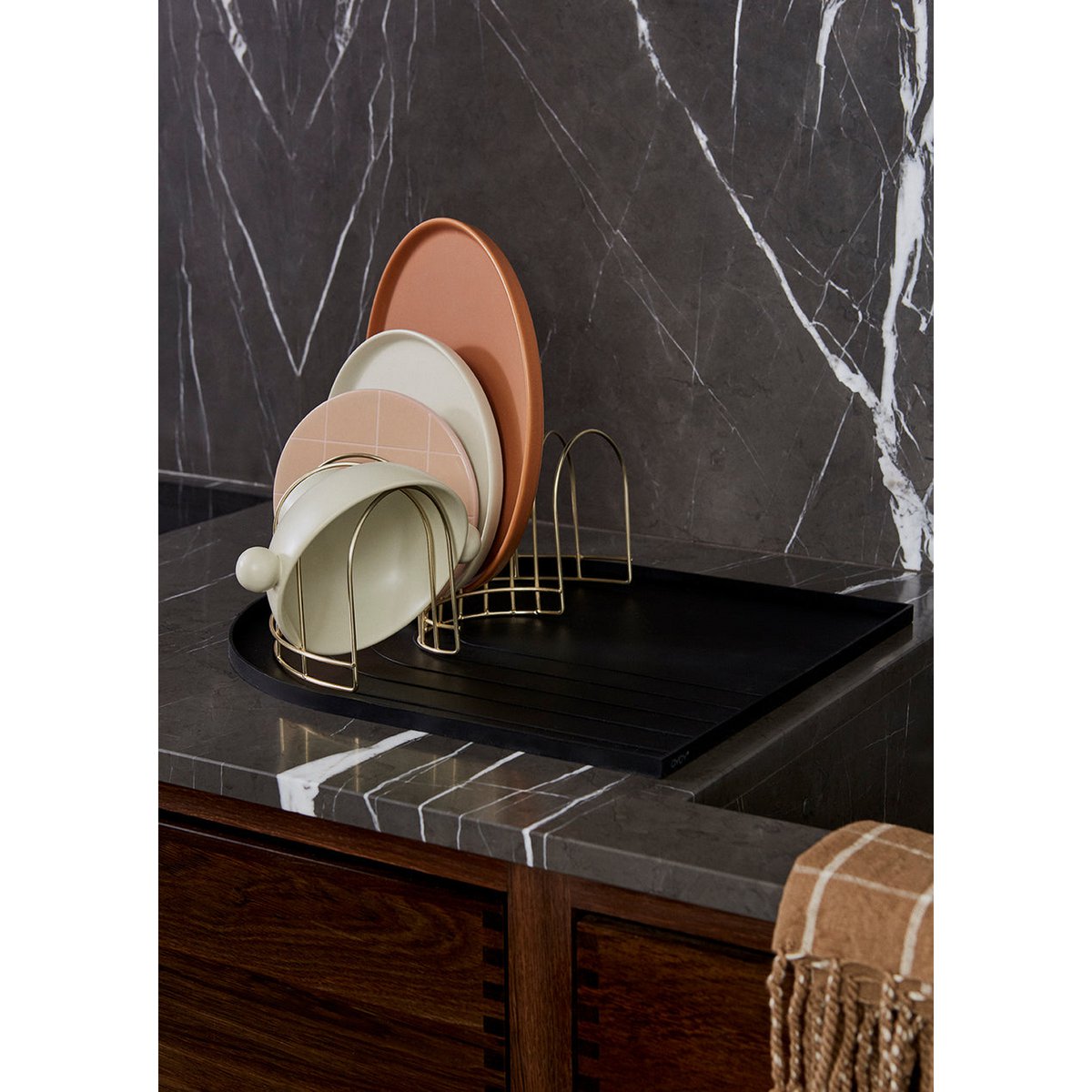 Stack of ceramic plates on a wire rack against a marble backsplash.