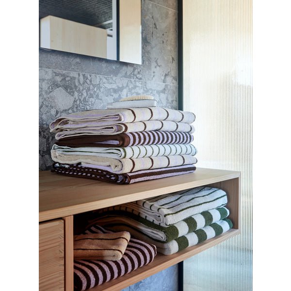 Stack of folded towels on a wooden shelf with a neutral background