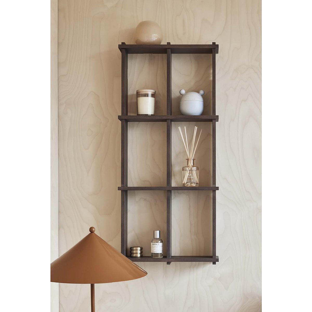 Wall-mounted shelf with decorative items against a light wood panel background