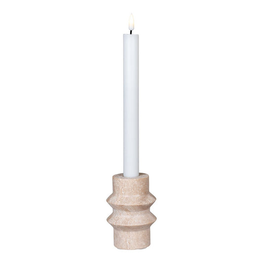 White candle in a natural travertine ceramic holder on a white background