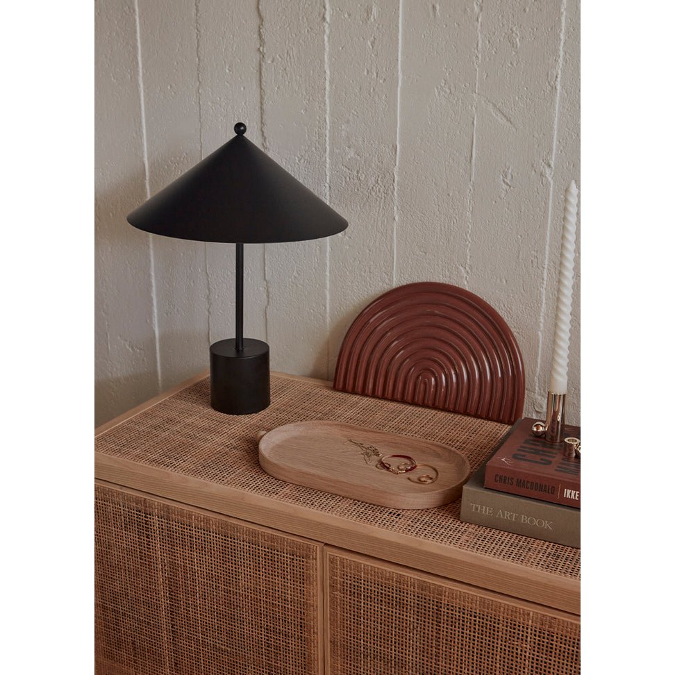 Black table lamp on a wooden surface with a textured wall background